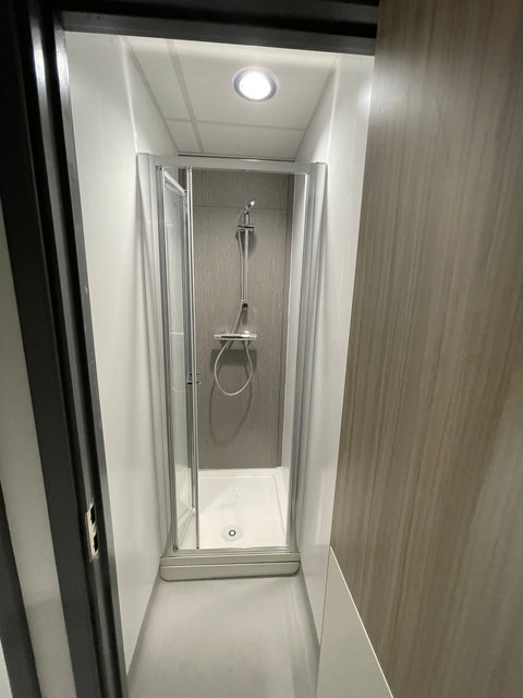 Grey woodgrain IPS panelling inside a hospital shower, behind the shower valve and riser