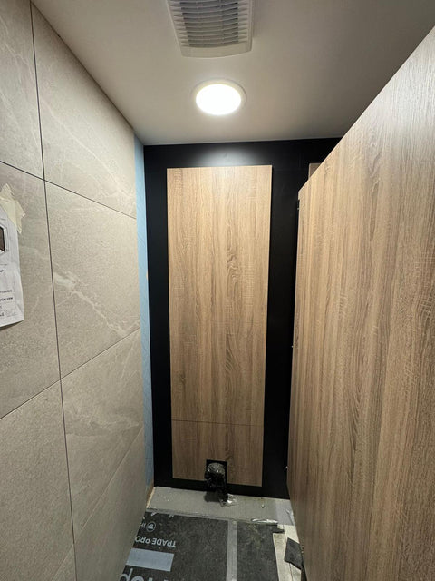 An Ascent Range woodgrain cubicle partition beside a matching IPS panel behind the WC, during installation