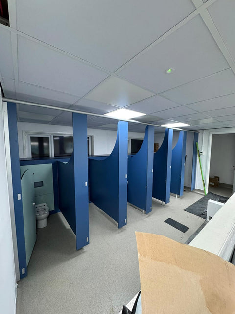 A run of Blossom Range nursery cubicles with curved blue pilasters, half-height IPS behind the WC, during installation
