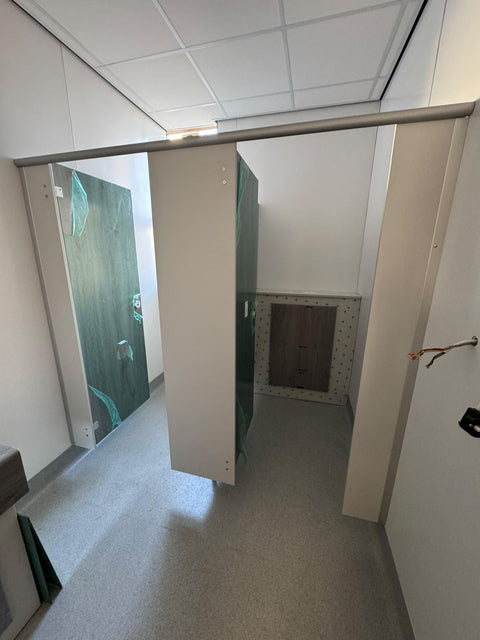 Half-height IPS with a grey woodgrain access panel behind a WC, inside Smart Range cubicles with green doors still in protective film