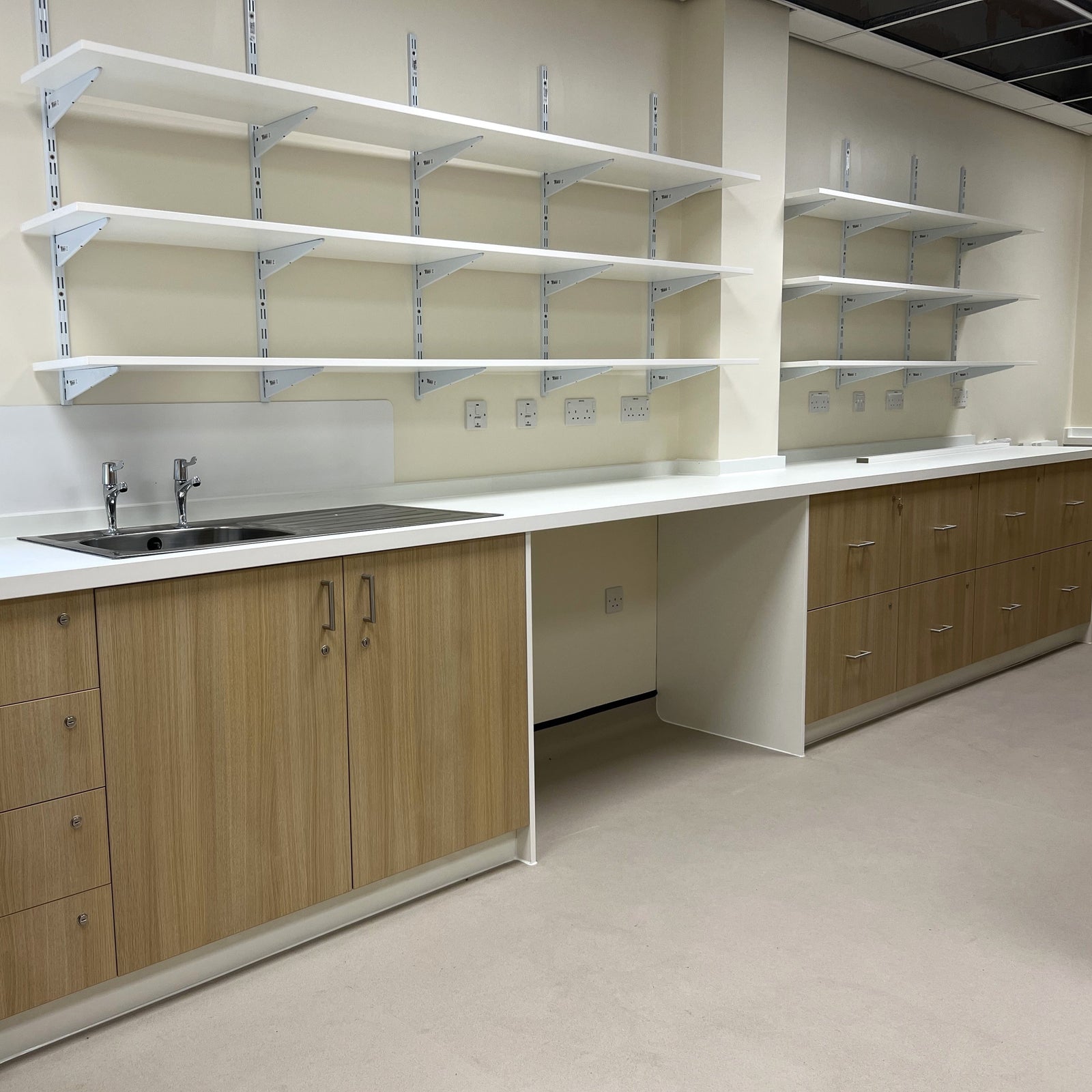 White wall-mounted spur shelving with MFC shelves in clinical environment