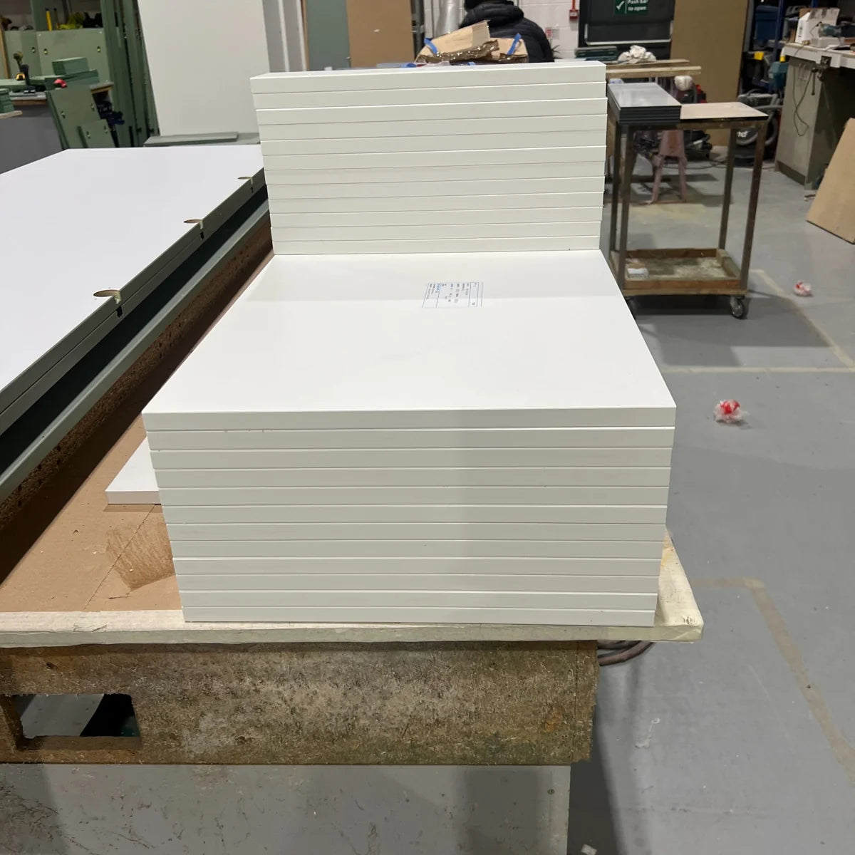 Stack of cut-to-size MFC panels with white PVC edge banding on a workshop bench